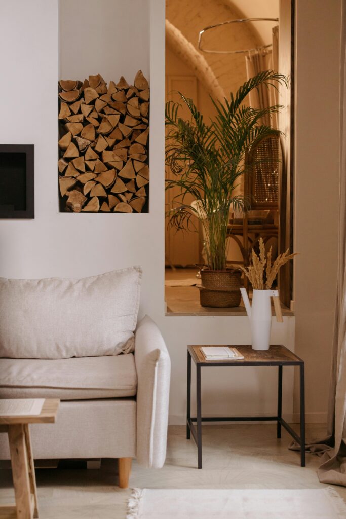 Stylish living room featuring a beige sofa, indoor plants, and a stack of firewood, perfect for modern interiors.